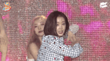 two women are dancing in front of a screen that says gkpop