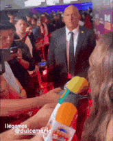 a man in a suit and tie stands in front of a crowd with dulcemaria written on the bottom