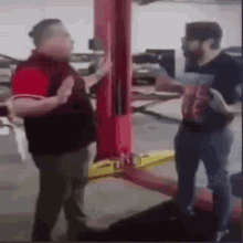 two men are standing next to each other in a garage and talking .