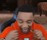 a man in an orange shirt is eating a piece of chocolate