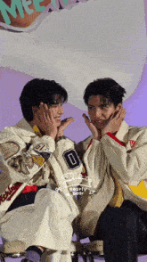 two young men are sitting next to each other and one of them has the number 0 on his jacket