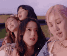 a group of young women are sitting in a car and one of them has pink hair