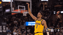 a basketball player wearing a yellow indiana jersey reaches for the basketball hoop