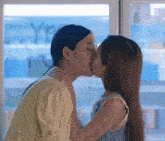 two women are kissing in front of a window with the word yes written on it