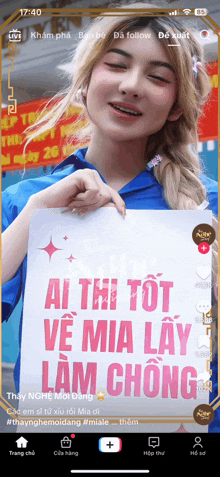 a woman holding a sign that says " ai thi tot ve mia lay lam chong "