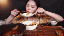 a woman is eating food with chopsticks from a bowl