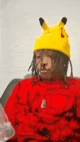 a person wearing a yellow pikachu hat and a red sweater .