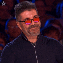 a man wearing sunglasses is smiling in front of a crowd with a star in the corner