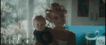 a woman with curlers on her hair is holding a baby in her arms