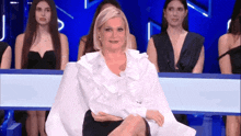 a woman is sitting in a chair with her legs crossed in front of a crowd of women .