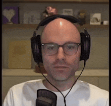 a bald man wearing glasses and headphones is looking at the camera