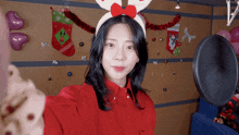 a woman wearing a reindeer headband is taking a selfie in front of a microphone
