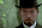 a man with a beard wearing a top hat looks at the camera