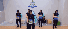 a group of young men are dancing in a room with a sign that says ecm on it