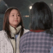 two women are standing next to each other and looking at each other .
