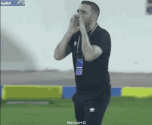 a man in a black shirt and white shorts stands on a soccer field with the words whdahd on the bottom right
