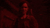 a woman is standing in a dark room with a red light shining on her face .