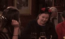 a group of women are sitting at a table with wine glasses and confetti falling