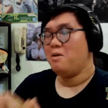 a man wearing glasses and headphones is sitting in front of a wall with a picture of a woman on it