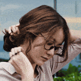 a woman wearing glasses holds her hair in a bun with the words like a princess below her