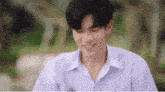 a young man in a white shirt is smiling while sitting down .