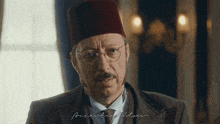 a man wearing a hat and glasses is standing in a room .
