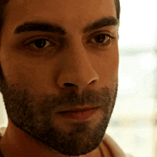 a close up of a man 's face with a beard looking at the camera
