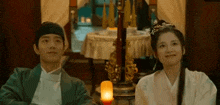 a man and a woman are sitting next to each other in a room with candles .