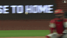 a baseball player catching a ball in front of a sign that says " be to home "