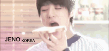 a young boy is eating a piece of bread with the name jeno korea written on the bottom