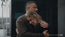 a man and a woman are hugging each other in front of a building .