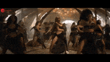 a group of women are dancing in a room with a chandelier .