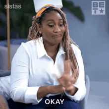 a woman in a white shirt is clapping her hands and saying okay .