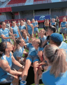 a group of female soccer players including one wearing a blue shirt that says ' liga ' on it