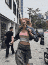 a woman is walking down a sidewalk with a man walking behind her