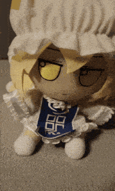 a stuffed doll with a white hat and a blue apron that says " r " on it