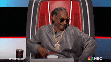 snoop dogg is sitting in a chair with the nbc logo on the bottom