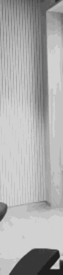 a black and white photo of a chair in a room with a white wall behind it .