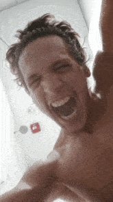 a man without a shirt is screaming with his mouth wide open