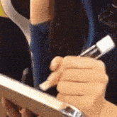 a close up of a person holding a cell phone and a pen in their hand .