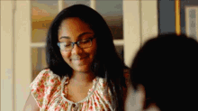 a young girl wearing glasses and a floral top smiles