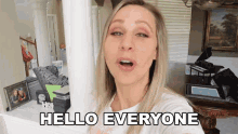 a blonde woman says hello everyone in a living room