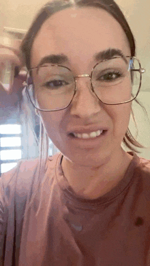 a close up of a woman wearing glasses and a pink shirt