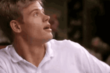 a man in a white shirt is sitting at a table and looking up .