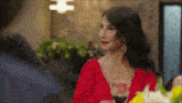 a woman in a red top is sitting at a table with a glass of wine