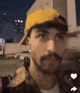 a man with a beard and mustache is wearing a yellow hat and a jacket .