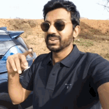 a man wearing sunglasses and a gant polo shirt is pointing at something