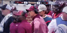 a group of men are watching a football game and one of them is wearing a shirt that says vt
