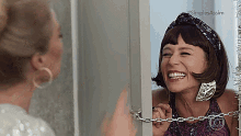 a woman is chained to a door and smiling in front of a mirror