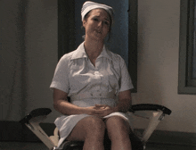 a nurse is sitting in a chair with her hands folded